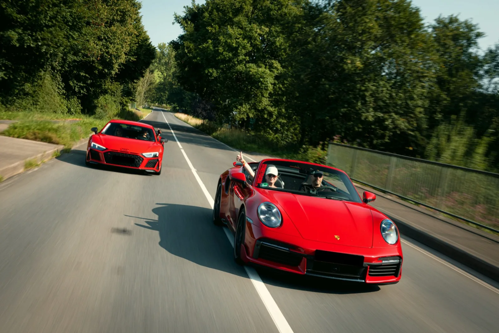 Rode Porsche 911 cabriolet en rode Audi R8 op een landweg