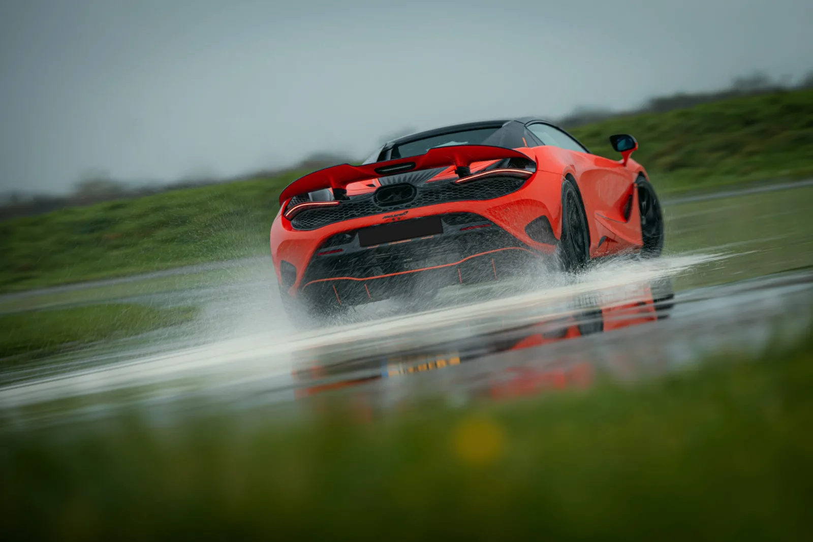 Oranje McLaren 750S Spider op een nat circuit